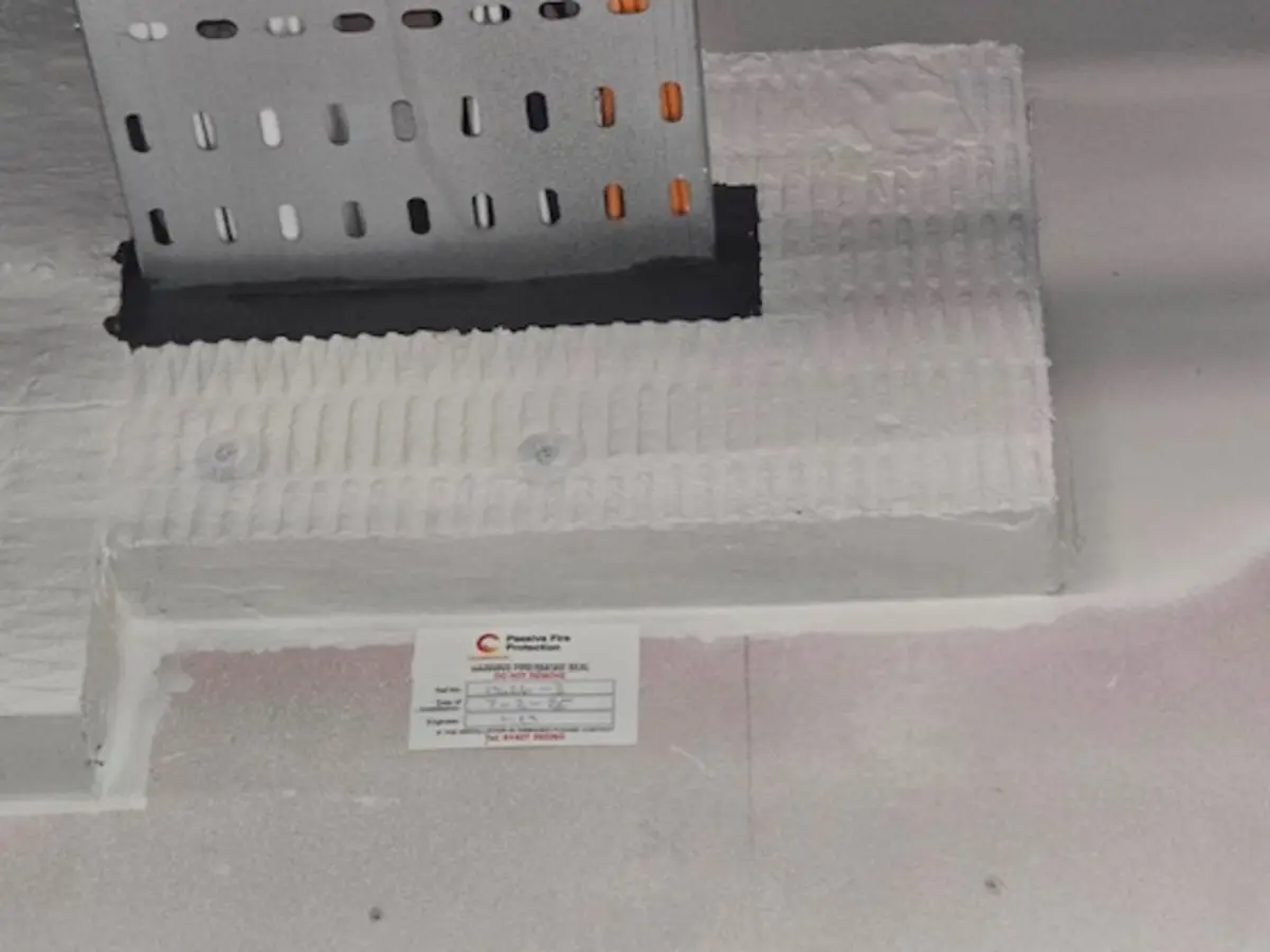 Close view of a labelled fire-stopping detail around metal cable containment
